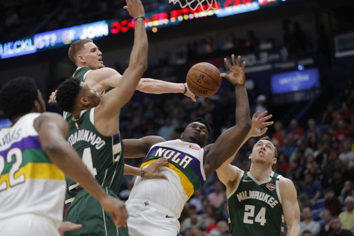 New Orleans Pelicans forward Zion Williamson is fouled as he goes to the basket between Milwaukee Bucks guard Pat Connaughton (24), forward Giannis Antetokounmpo (34) and guard Donte DiVincenzo in the first half of an NBA basketball game in New Orleans, Tuesday, Feb. 4, 2020. (AP Photo/Gerald Herbert)