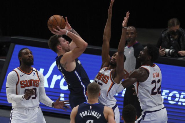 Dallas Mavericks guard Luka Doncic (77) shoots against Phoenix Suns forward Mikal Bridges (25) and center Deandre Ayton (22) in the first half during an NBA basketball game, Monday, Feb. 1, 2021, in Dallas. (AP Photo/ Richard W. Rodriguez)