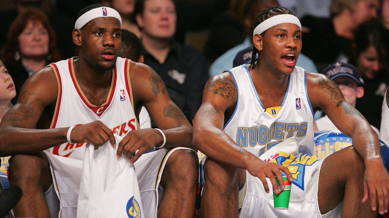 DENVER - FEBRUARY 18: (L-R) LeBron James #23 and Carmelo Anthony #15 of the Sophomore Team cheer on their teammates against the Rookie Team during the got milk? Rookie Challenge, part of 2005 NBA All-Star Weekend at Pepsi Center on February 18, 2005 in Denver, Colorado. NOTE TO USER: User expressly acknowledges and agrees that, by downloading and/or using this Photograph, user is consenting to the terms and conditions of the Getty Images License Agreement. (Photo by Ezra Shaw/Getty Images)